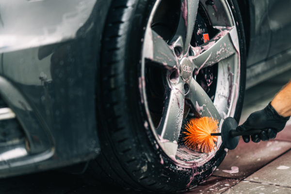 A detailer wearing a glove uses a ADBL's Wheel Sword to clean in between a wheel's rim spokes.