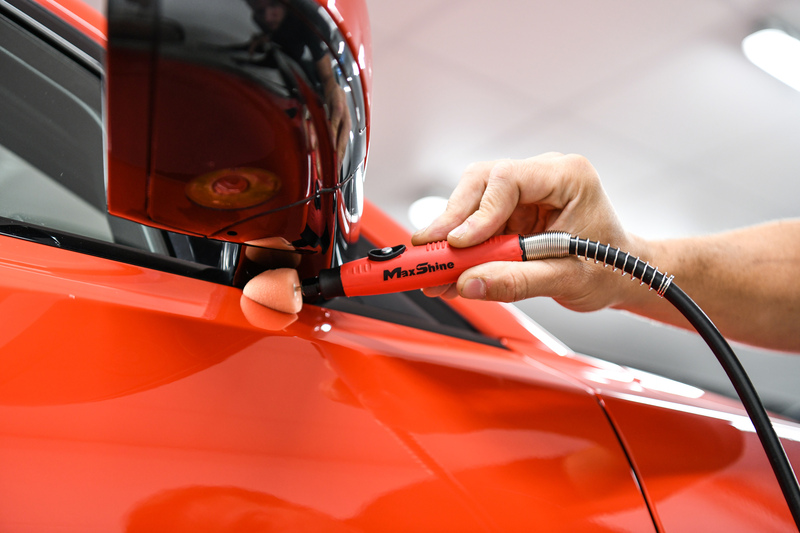maxshine-mini-polishing-system-precision-car-polishing.jpg Maxshine Mini Polishing System being used with a small orange foam polishing cone to polish tight paintwork around a red car's wing mirror.